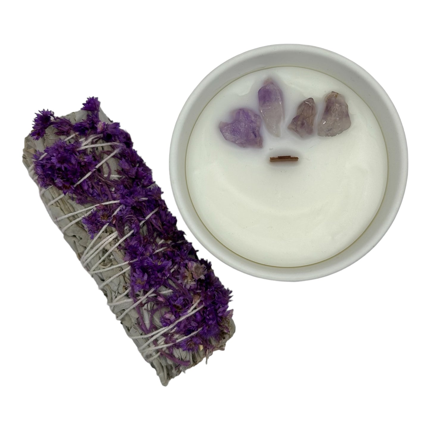 Top view of 4 oz Lavender Fields candle with wooden wick and amethyst crystals on top, accompanied by a sage bundle with flowers on the side, set against a white background for a soothing, aromatic experience