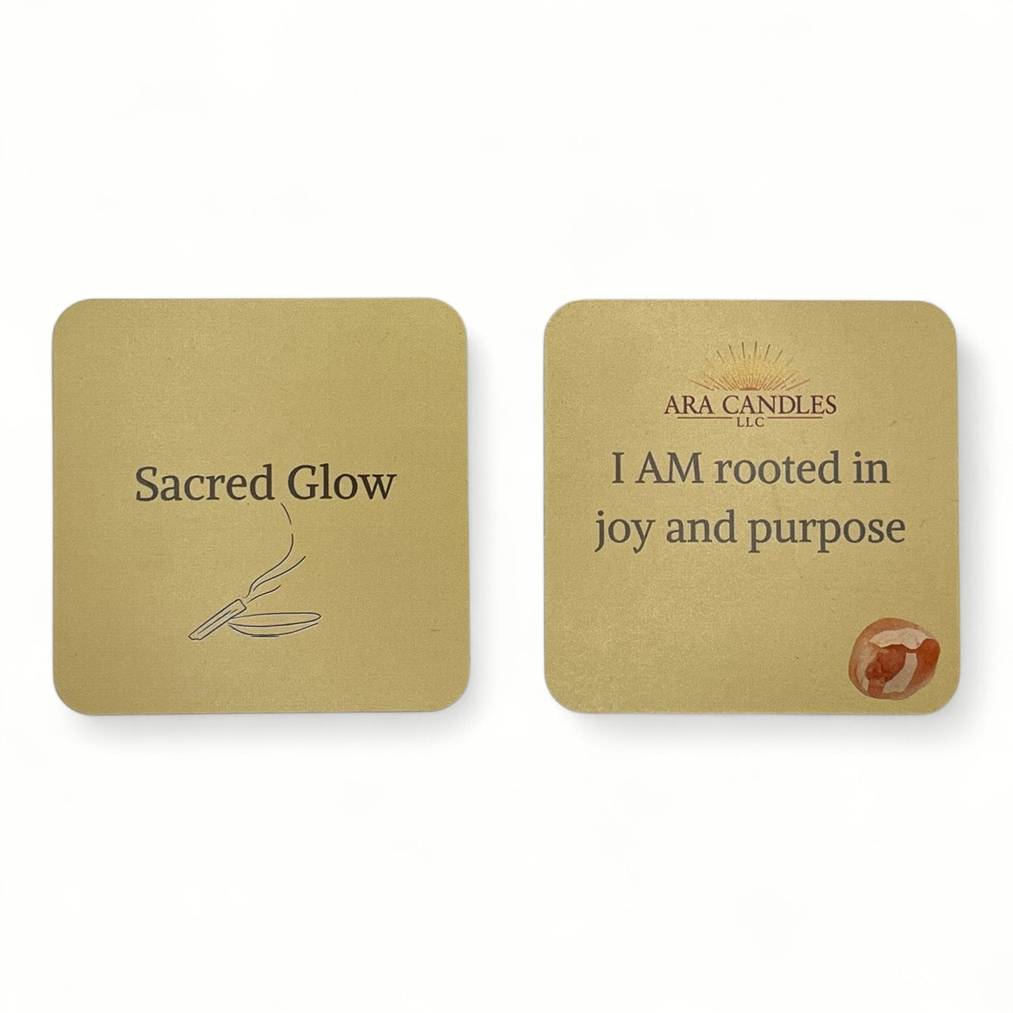SACRED GLOW affirmation card set from ARA Candles, in golden tones with palo santo illustration and the quote "I AM rooted in joy and purpose" accented with a grounding crystal.