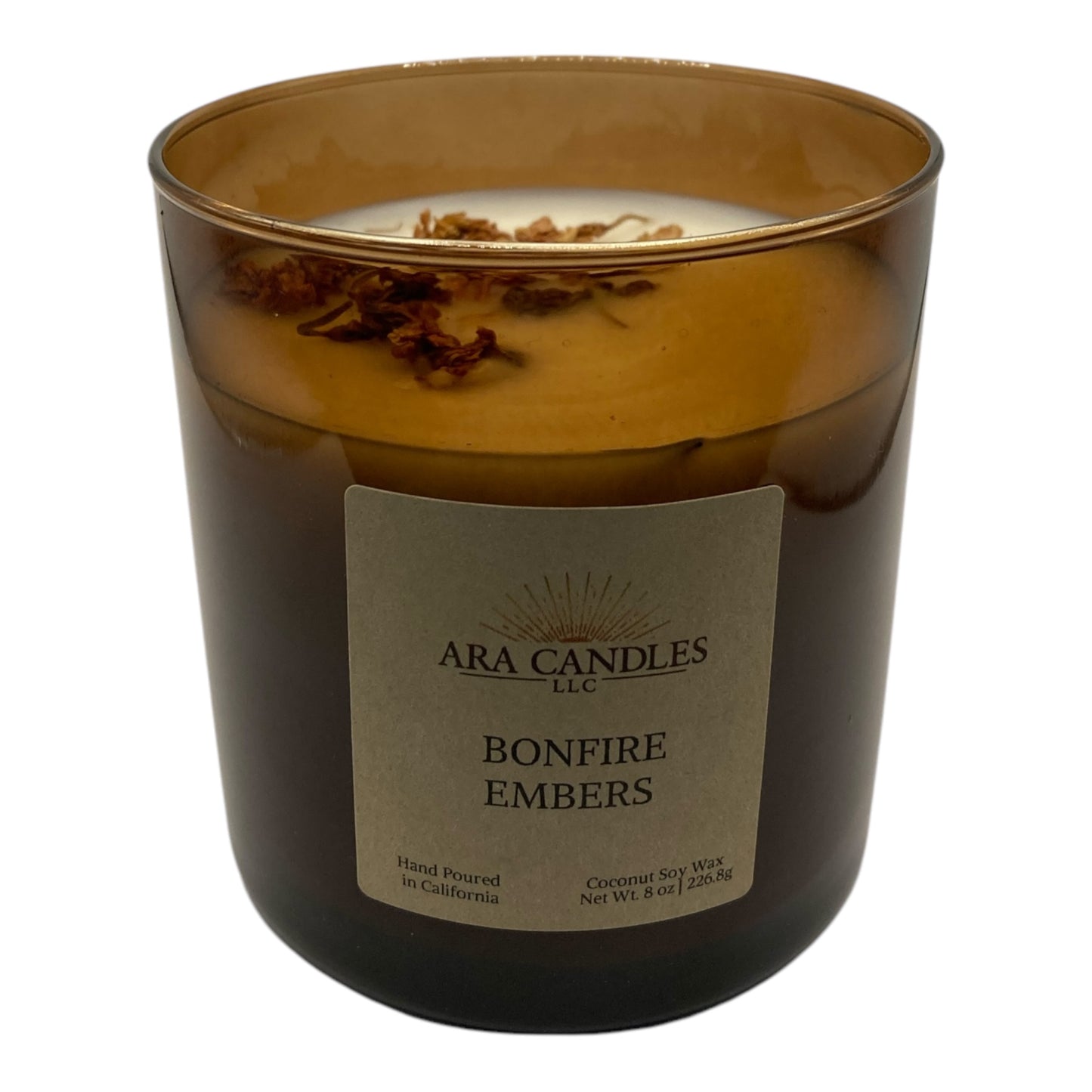 Bonfire Embers flameless 8 oz candle in an amber jar with dried leaves on top, set against a white background, offering a warm, smoky bonfire fragrance for a cozy, flame-free ambiance