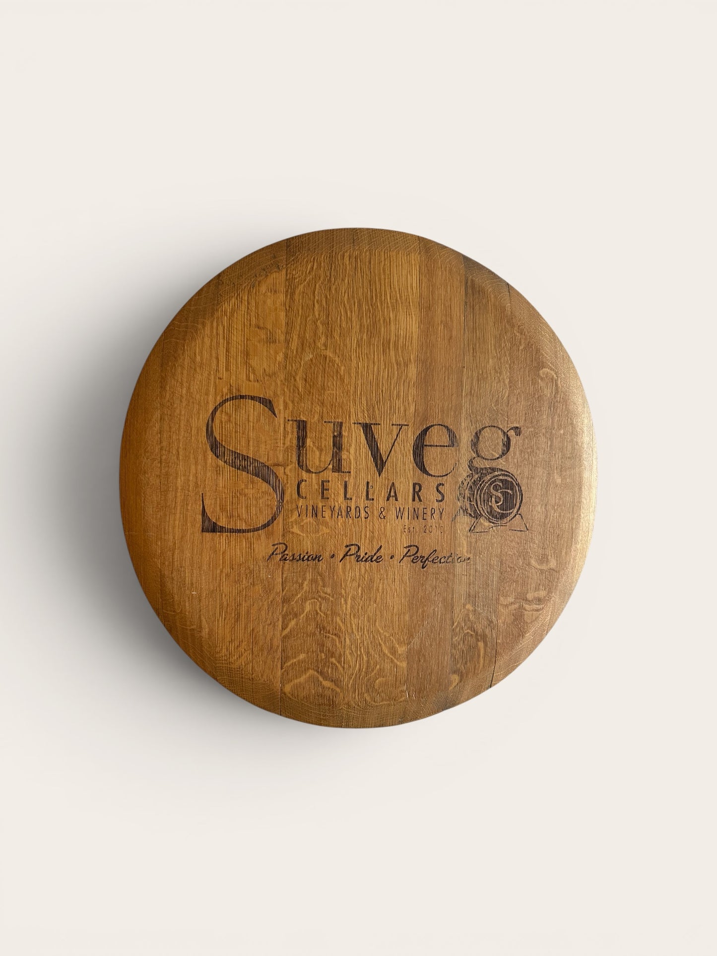 Wooden wine barrel lid with 'Suveg Cellars' branding on a light gray background