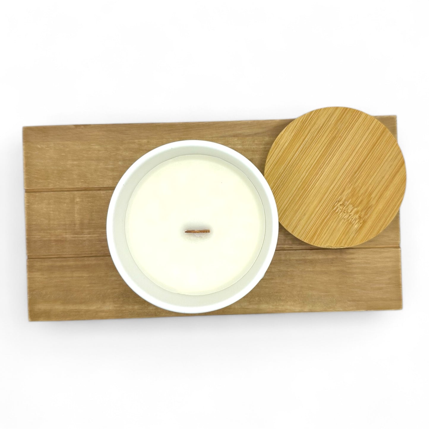 Top-down view of Sacred Glow candle in white ceramic vessel with wooden lid on bamboo tray, showcasing creamy coconut soy wax and centered wood wick.