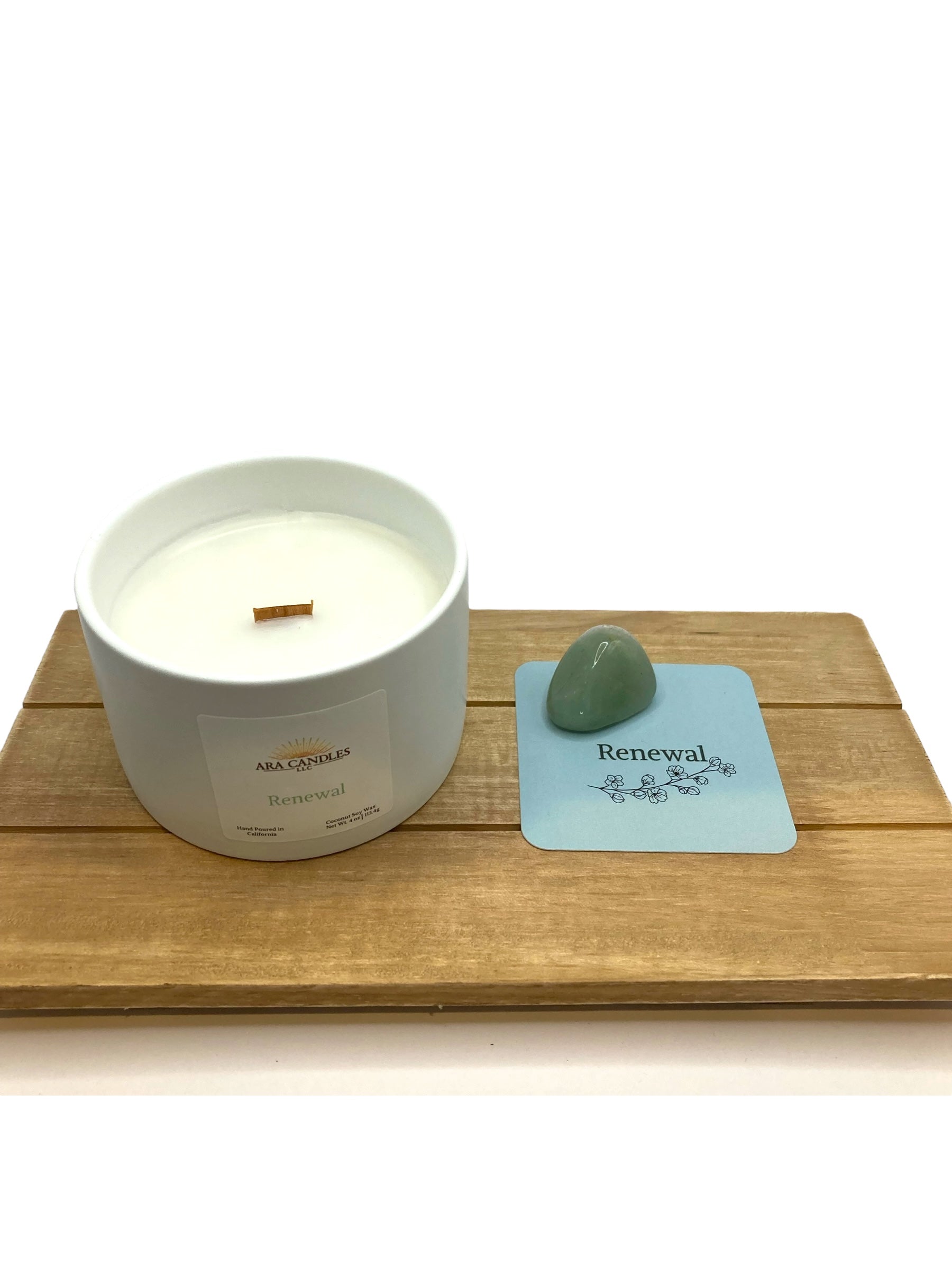 Renewal candle displayed on a wooden tray with a green aventurine stone and blue affirmation card.