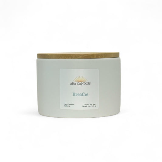 White ceramic candle labeled Breathe from Ara Candles, with wooden lid, designed for clarity and breath work rituals.