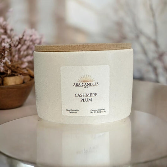 Ara Candles Cashmere Plum coconut soy candle, featuring a rich plum and soft cashmere scent, styled in a cozy setting with warm tones and minimalist decor