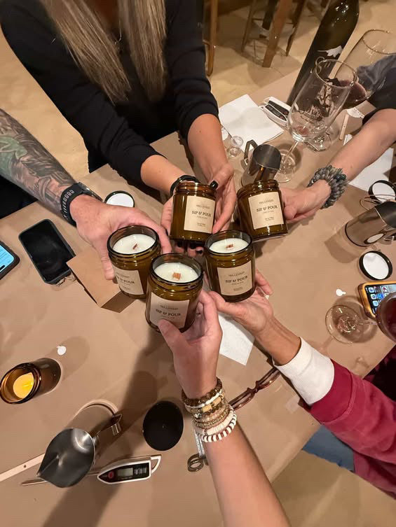 Guests raising their handmade Sip & Pour candles together at an Ara Candles gathering